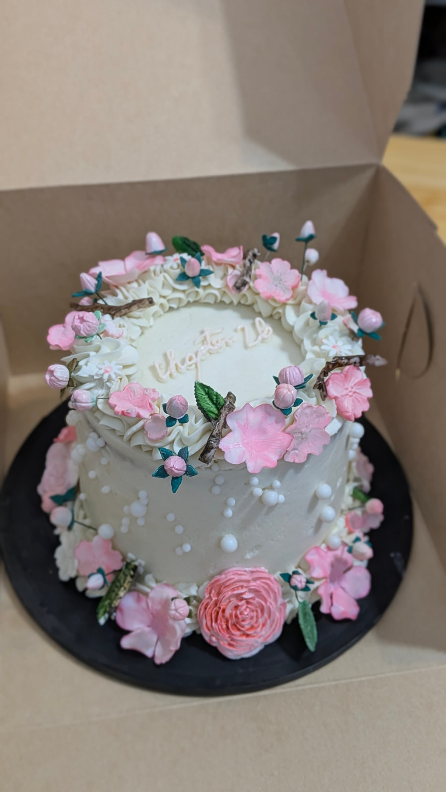 Round anniversary cake ringed with pink and white piped flowers