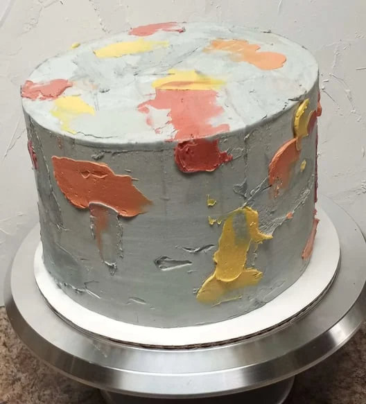 Grey cement-effect Swiss buttercream cake with orange, yellow and red brushstrokes