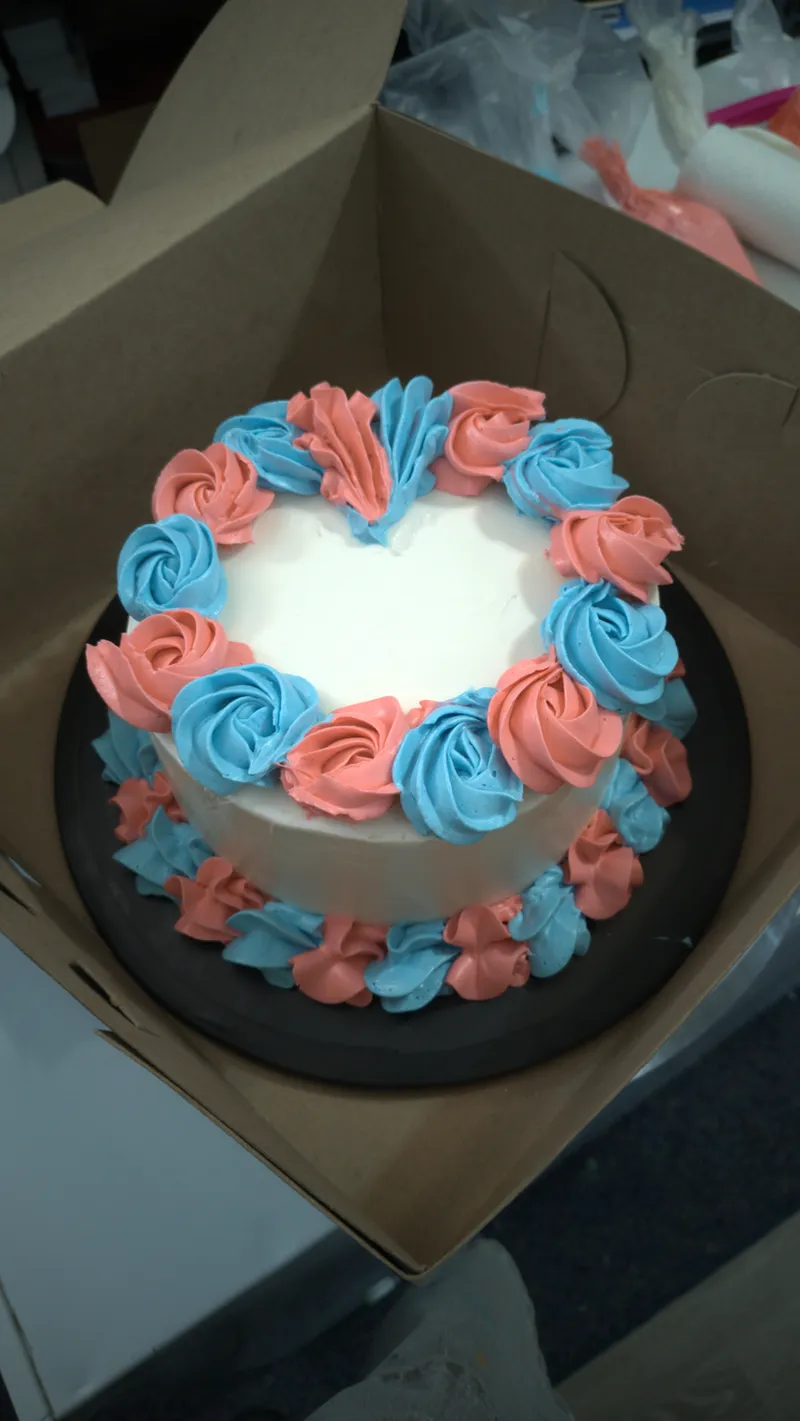 White cake ringed with coral and blue buttercream rosettes
