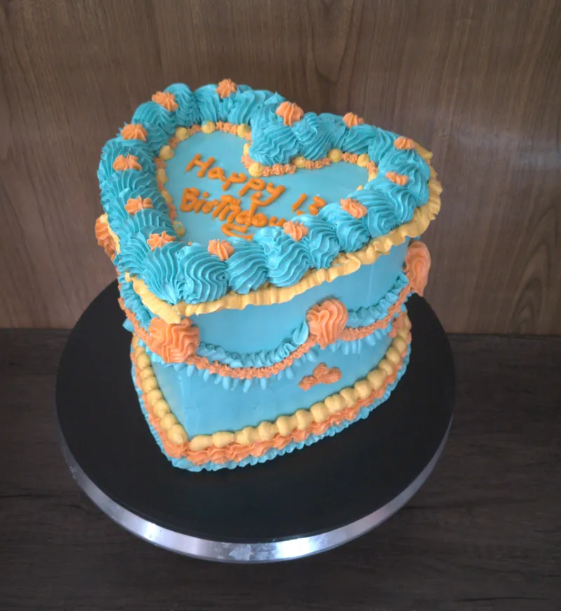 Heart-shaped turquoise cake with orange vintage-style piping