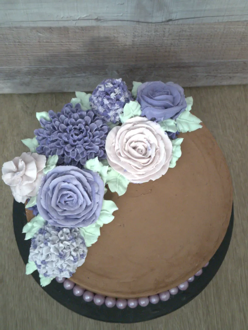 Chocolate-iced cake with a cascade of lavender and cream buttercream roses