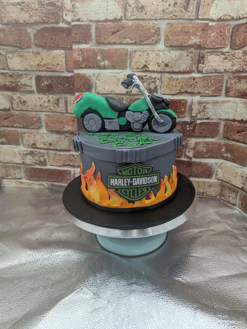 Motorcycle-themed birthday cake with flame sides and a green motorcycle on top
