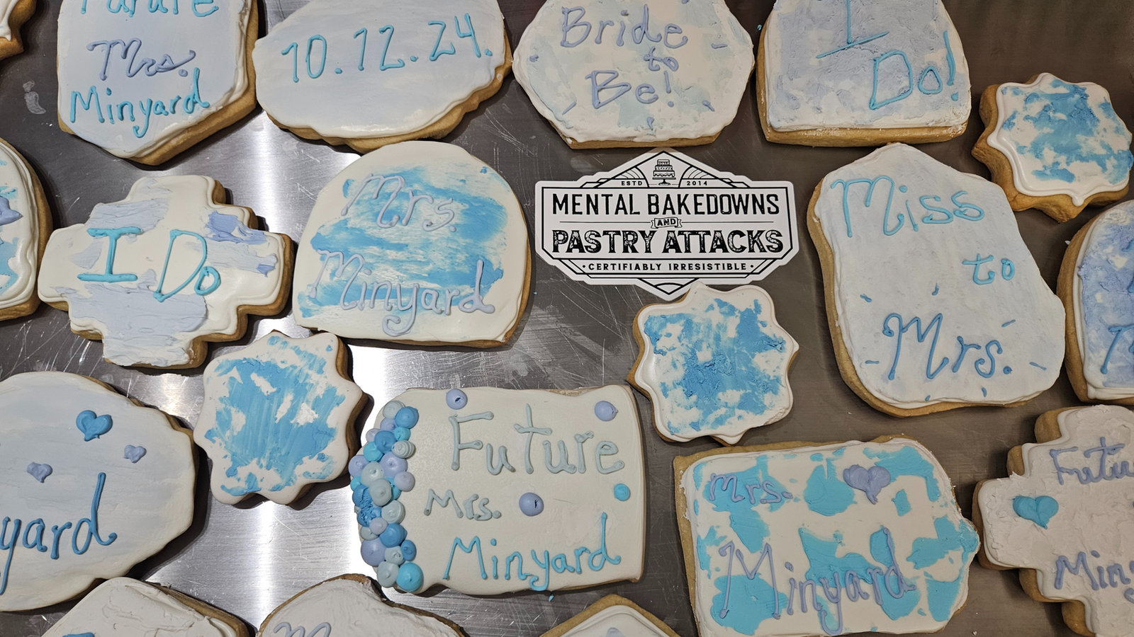 Blue and white bridal shower cookies reading I Do, Bride to Be, Miss to Mrs. and Future Mrs., with a Mental Bakedowns & Pastry Attacks plaque