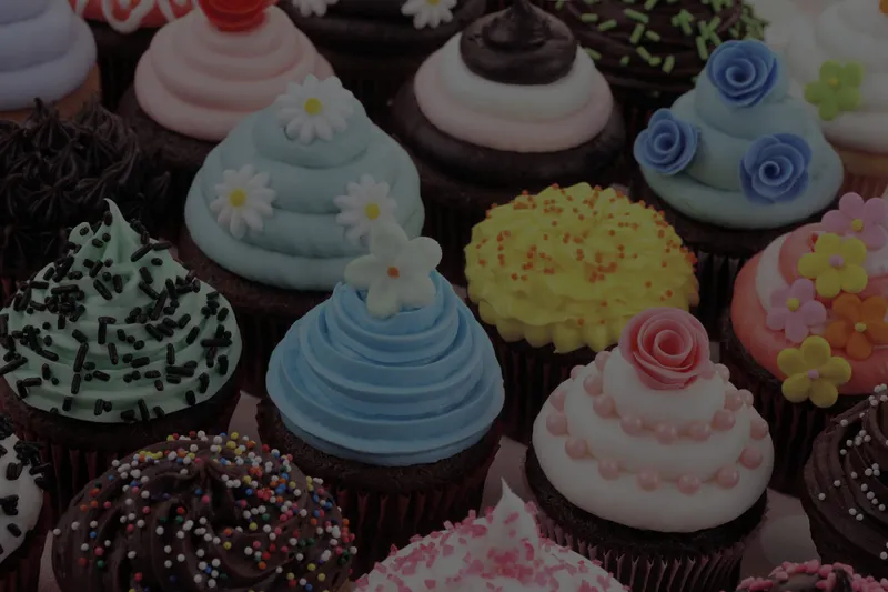 Assorted cupcakes with blue, pink, green and yellow buttercream swirls and sprinkles