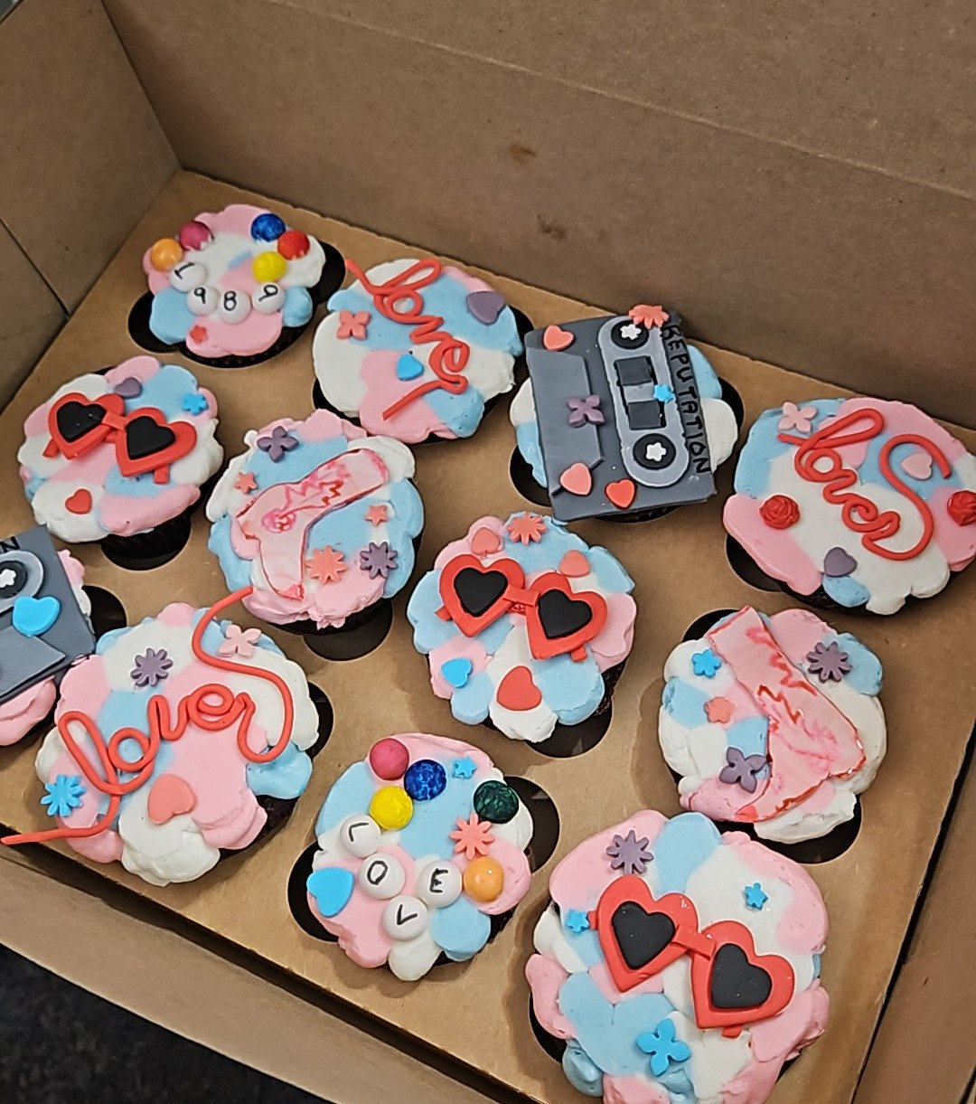 Cupcakes with fondant toppers including heart sunglasses, a cassette tape and the word love